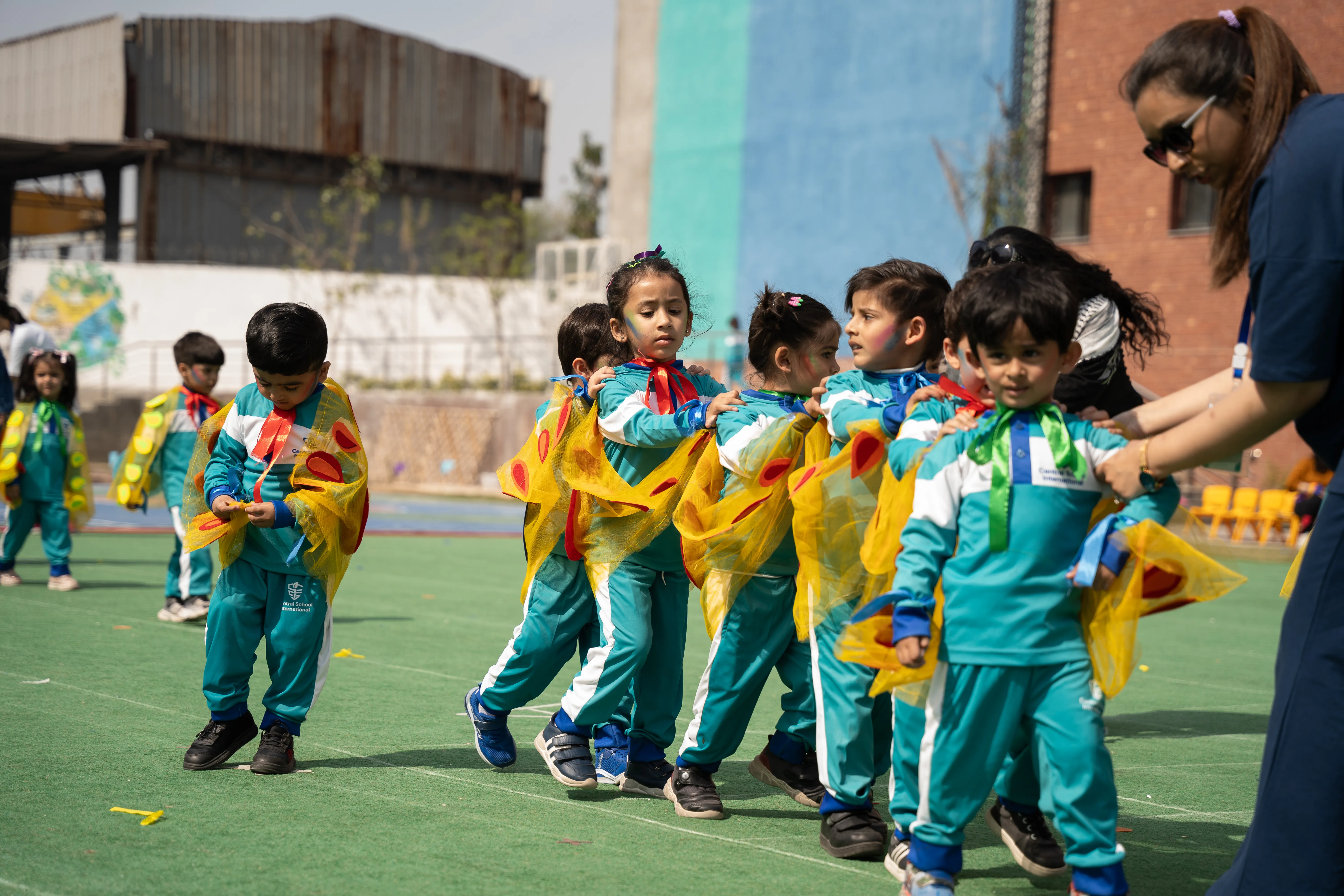 CSI young children moving together outdoors with their teacher.